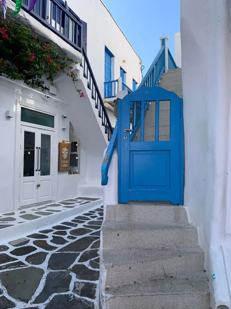 A whitewashed terrace with a blue door and stairs