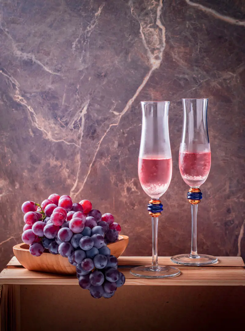 Two glasses of rosé with grapes on a table
